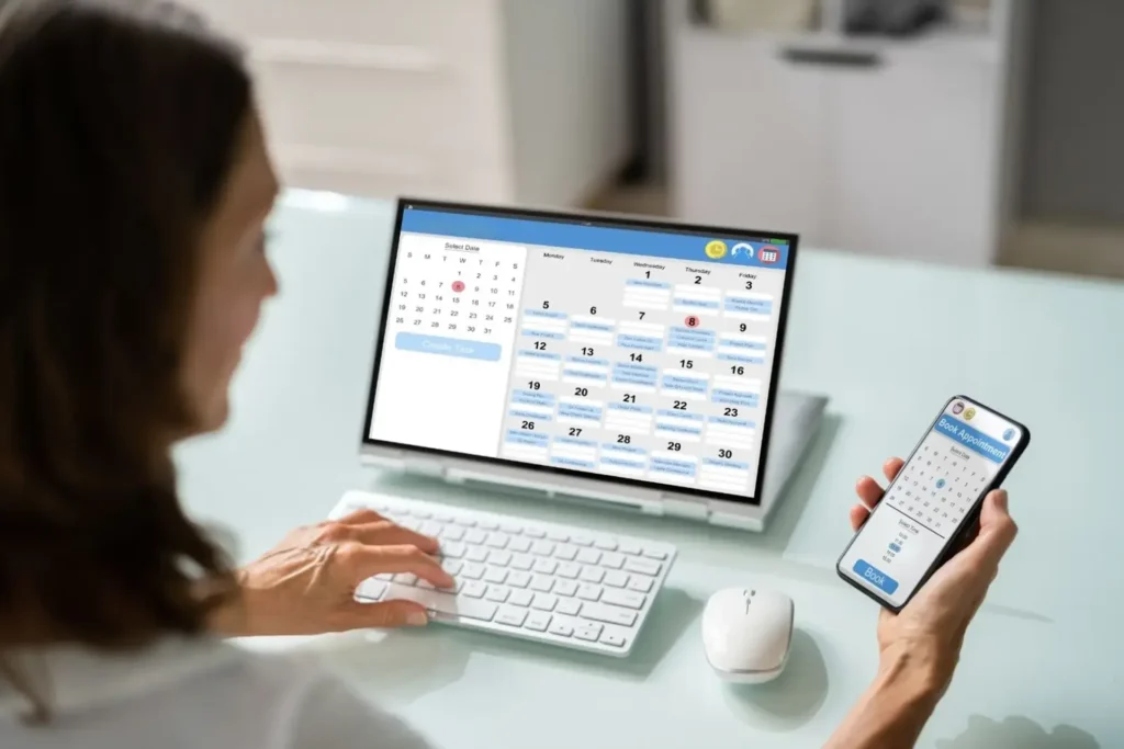 Woman uses a laptop and smartphone to review her calendar for scheduling an appointment